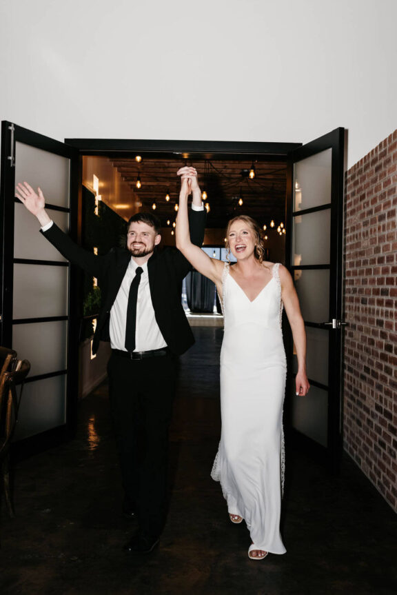 The bride and groom enter the reception through double frosted doors.