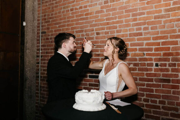 The bride and groom feed each other cake.