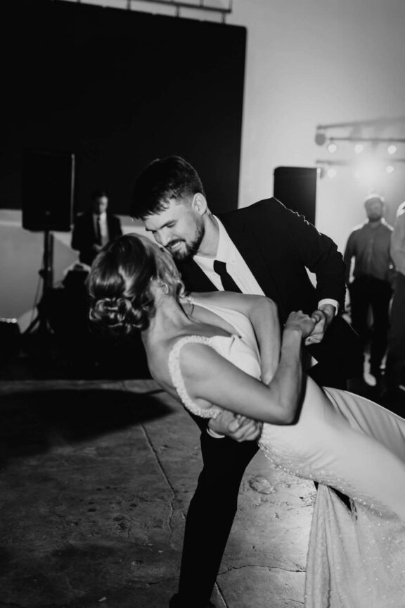 The groom dips the bride while dancing.