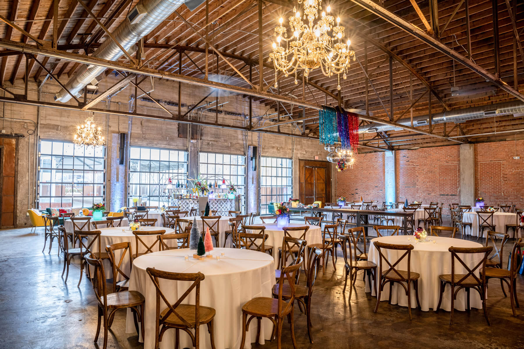 Interior of the venue featuring brick walls, chandelier, and round tables setup for an event.