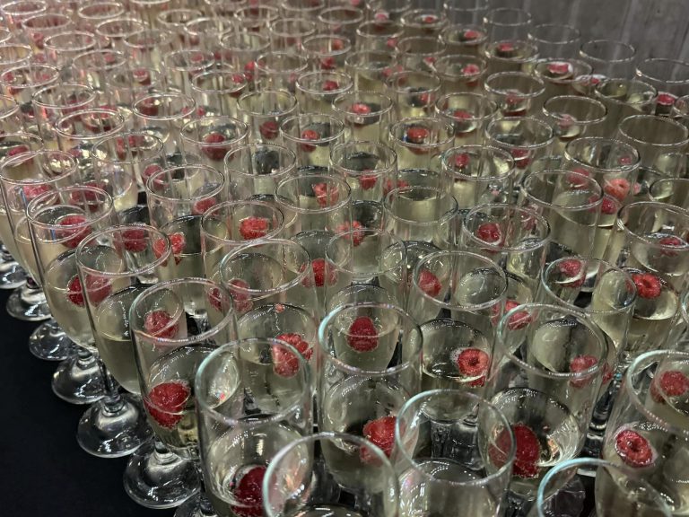 View over the top of a table covered in champagne glasses with raspberries.