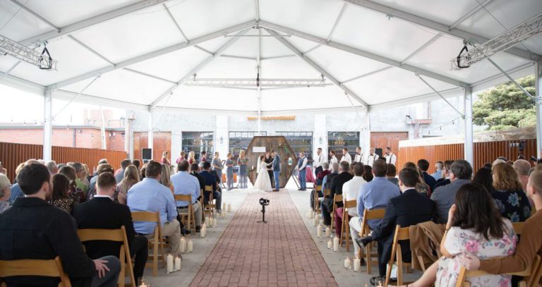 Guest seated at outdoor wedding inside large tent