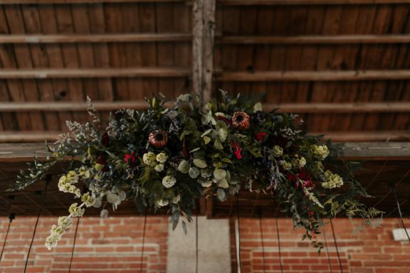 Wedding flowers hanging from wood rafters